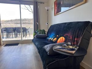 a black couch in a living room with a table at L'abeille sous les étoiles in Saint-Michel-lʼObservatoire