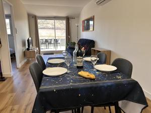 a dining room table with a bottle of wine and glasses at L'abeille sous les étoiles in Saint-Michel-lʼObservatoire