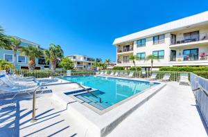 a swimming pool with chairs and a building at Anna Maria Island Beach View 207 in Bradenton Beach