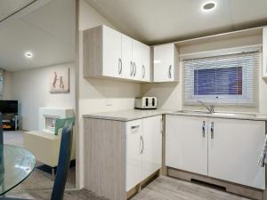 a kitchen with white cabinets and a glass table at The Paddocks - Uk7112 in Alloa +11 photos