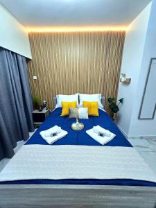 a bedroom with a large blue bed with yellow pillows at Marble Coast Studio Apartment in Larnaca +36 photos