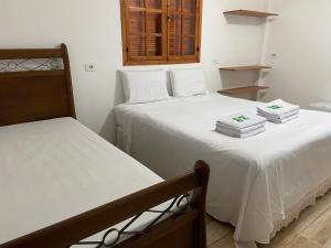 two beds in a room with white sheets at Pousada casa amarela Analândia SP in Analândia +208 photos