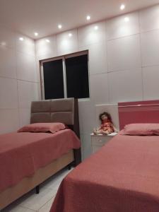 a bedroom with two beds and a teddy bear sitting on a counter at Acomodações em Bananeiras, PB in Bananeiras