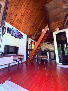 a living room with a wooden floor and a staircase at Chalé Sertão da Boa Vista in Rio Claro