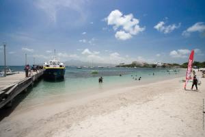 a boat docked at a beach with people in the water at Résidence Les A'Rhum de l'Anse in Les Trois-Îlets