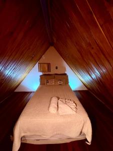 a bedroom with a bed in a wooden room at Chalé Sertão da Boa Vista in Rio Claro