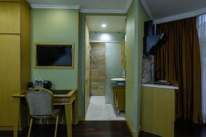 a room with a desk and a television and a bathroom at LUVERDE HOTEL Sarkand in Almaty