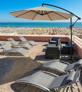 a group of chairs and an umbrella on the beach at Hotel Bel Air Frontemare in Rimini