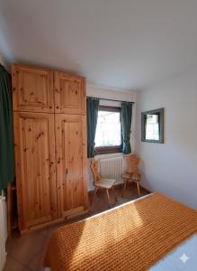a bedroom with a bed and a large wooden cabinet at Lo chalet di Lucky in Campodolcino