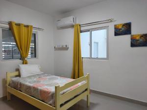 a bedroom with a bed with yellow curtains and a window at América Colares VII in Los Frailes
