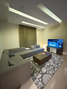 a living room with a couch and a flat screen tv at Olive Residence Madinah in Medina