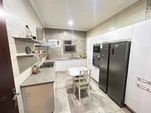 a kitchen with a black refrigerator and a table at Olive Residence Madinah in Medina