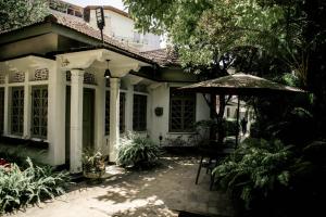 a white house with an umbrella and a patio at Hotel Mount Pleasant in Bandarawela