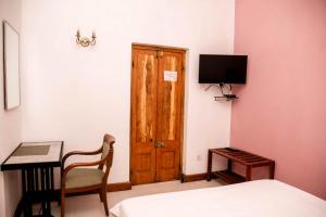 a bedroom with a bed and a desk and a door at Hotel Mount Pleasant in Bandarawela