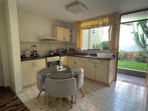 a kitchen with a table and chairs and a table and a kitchen with a window at Villa Salluzzi Apart Hotel in Tacna