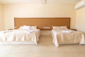 a bedroom with two beds with white sheets at Casa Nami in Puerto Escondido