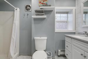 a white bathroom with a toilet and a sink at Downtown Casper Gem! Super Walkable Apartment in Casper +18 photos