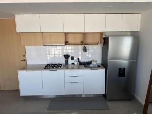 a kitchen with white cabinets and a stainless steel refrigerator at Luxury apartment near Andares in Guadalajara