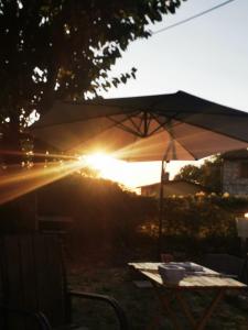 a table with an umbrella in front of the sunset at Piccola Sorpresa Il preferito degli escursionisti sul Cammino in Scoppieto
