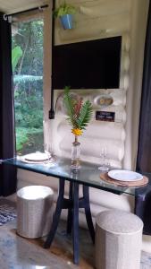 a glass table with two plates and a plant on it at Chalé Do Lago in Piracaia