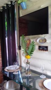 a table with two glasses and a vase with flowers at Chalé Do Lago in Piracaia