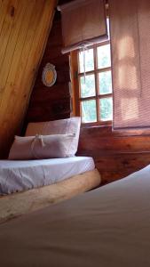 two beds in a wooden room with a window at Chalé Do Lago in Piracaia