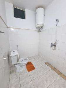 a bathroom with a toilet in a white tiled room at Vince Saly in Saly Portudal