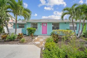 a blue house with a pink door and palm trees at pink peacock in Holmes Beach