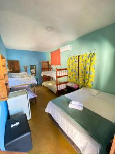 a bedroom with two beds and a room with two chairs at Pousada Conexão in Itaúnas