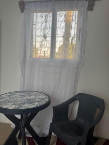 a table and a chair in front of a window at Simple house in Lyndiane Zig in Ziguinchor