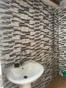 a white sink in a bathroom with mosaic tiles at Simple house in Lyndiane Zig in Ziguinchor