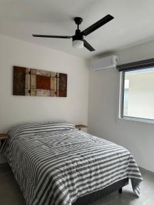 a white bedroom with a bed and a ceiling fan at Apartamento con acceso directo al río in Veracruz