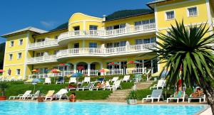 a large yellow building with chairs and a swimming pool at All Inclusive Hotel Sonnenhügel in Sattendorf