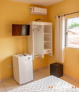 a room with a small refrigerator and a window at Hotel Leblon in Peruíbe