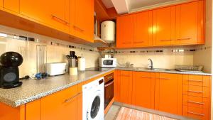 a kitchen with orange cabinets and a washing machine at Casa Dos Passos in Guarda