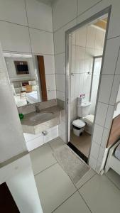 a bathroom with a sink and a toilet and a mirror at Hotel Hallas in Betim