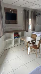 a living room with a tv and a table and chairs at Hotel Hallas in Betim