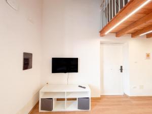 a white living room with a tv on a wall at CAERE RoGi House in Cerveteri