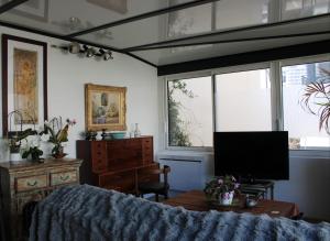 a bedroom with a bed and a tv and windows at Villa Danemark in Colombes