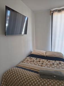 a bed in a room with a tv on the wall at Estudio Lavanda in Santa Rosa de Jáuregui