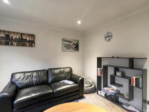 a living room with a leather couch and a book shelf at Achandoilach House in Strathcarron
