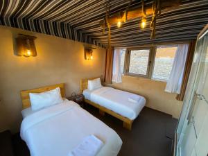 two beds in a room with two windows at Dana Trail Nomad Camp in Dana