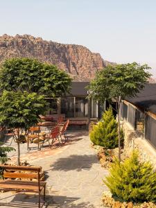 a house with benches and trees with a mountain in the background at Dana Trail Nomad Camp in Dana