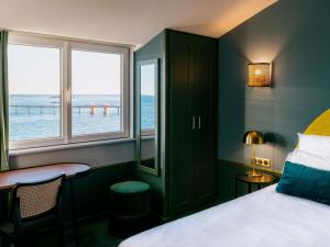 a bedroom with a bed and a view of the ocean at Hotel Mercure Roscoff Bord De Mer in Roscoff +190 photos