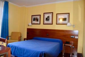 a bedroom with a blue bed and a chair at Hotel Vado del Duratón in Sepúlveda