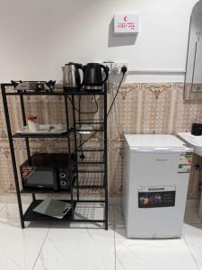 a shelf in a kitchen with a microwave and a refrigerator at شقق النبلاء in Medina