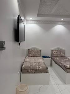 a room with two beds and a tv on the wall at شقق النبلاء in Medina
