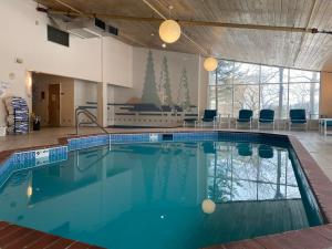 a large swimming pool in a room with chairs and tables at Aspen Lodge in Croftville
