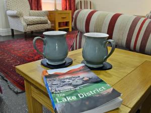 a table with two vases and a book on it at Fellmere in Ambleside