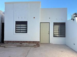 a white building with two windows and a yellow door at Modern 2-Bedroom House in Guaymas in Guaymas